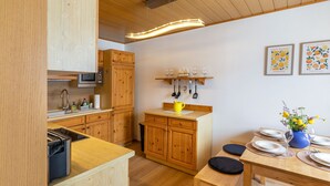 Une cuisine avec des meubles en bois, un four à micro-ondes et un coin repas avec une table mise pour deux personnes.