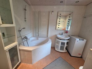 A bathroom with a bathtub, a shower, a sink, and a small refrigerator.