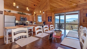 Una cabaña de madera con cocina, comedor y vistas a las montañas.