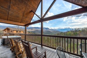 Una terraza de madera con un jacuzzi, sillas de madera y una mesa.