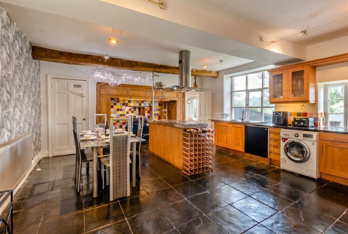 Een moderne keuken met een centraal eiland, houten kastjes en een ingebouwde wasmachine.