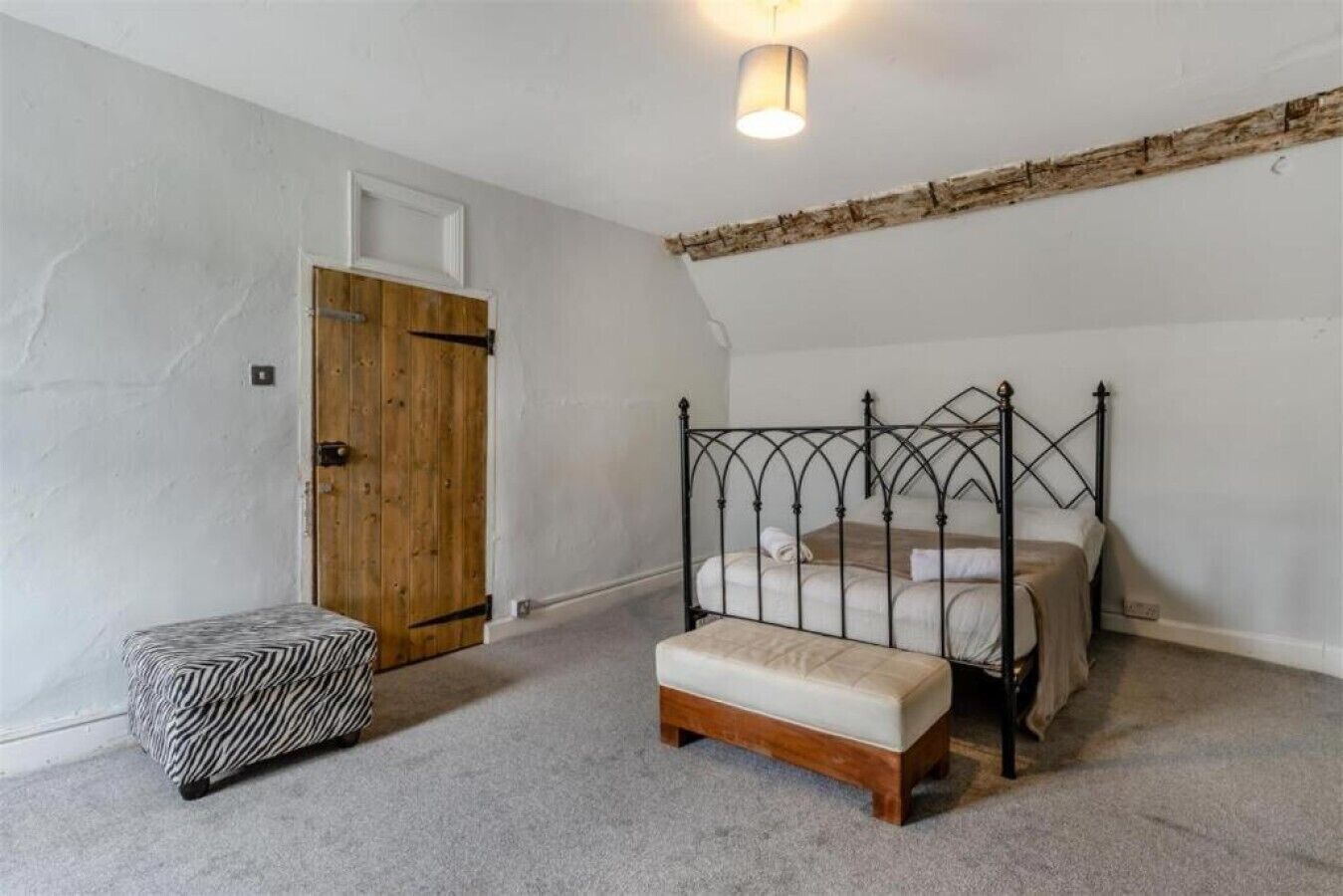 Un dormitorio con cama con dosel, una puerta de madera y un pequeño banco.