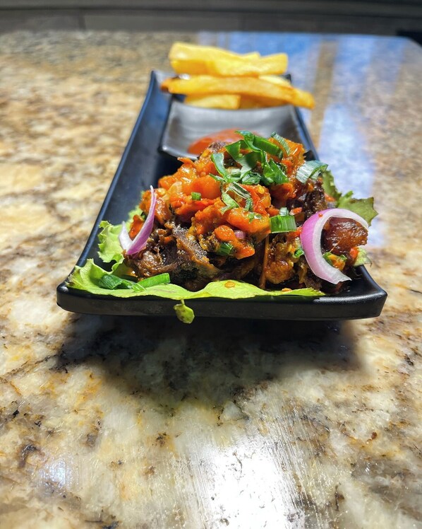 A dish with meat, vegetables, and a side of fries on a plate.