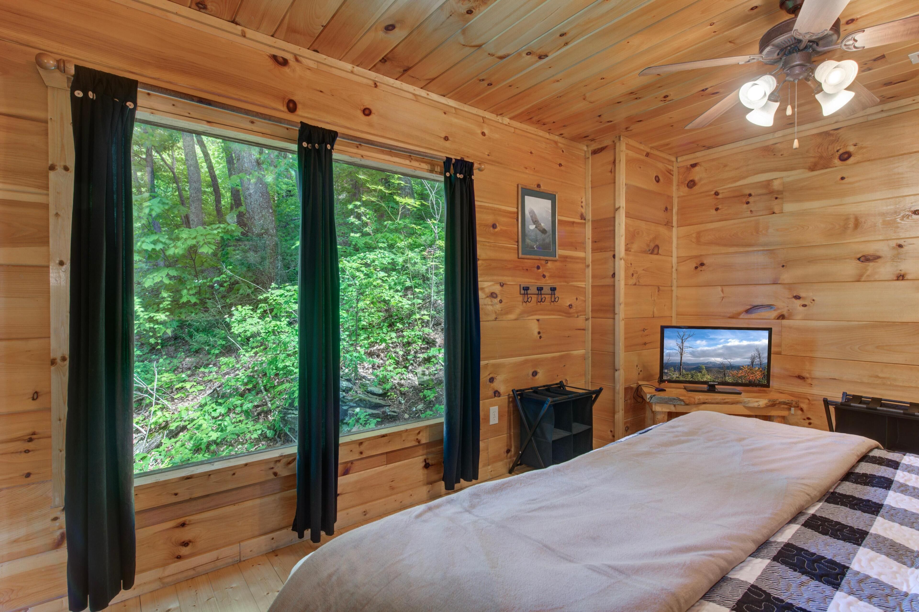 Une chambre dans un chalet en bois, avec un lit, une télévision et une fenêtre avec des rideaux.