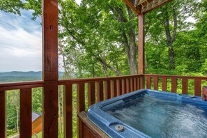 A hot tub on a wooden deck with a view of a forest and mountains. - All Time High (Sevierville)