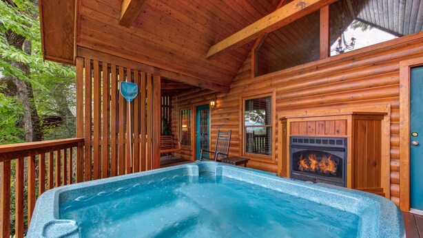 Eine Holzhütte mit Whirlpool, Kamin und einer Terrasse.