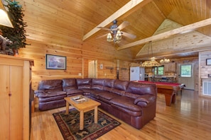 A wooden interior with a sectional sofa, a pool table, and a ceiling fan. - Hills Hideaway (Sevierville)