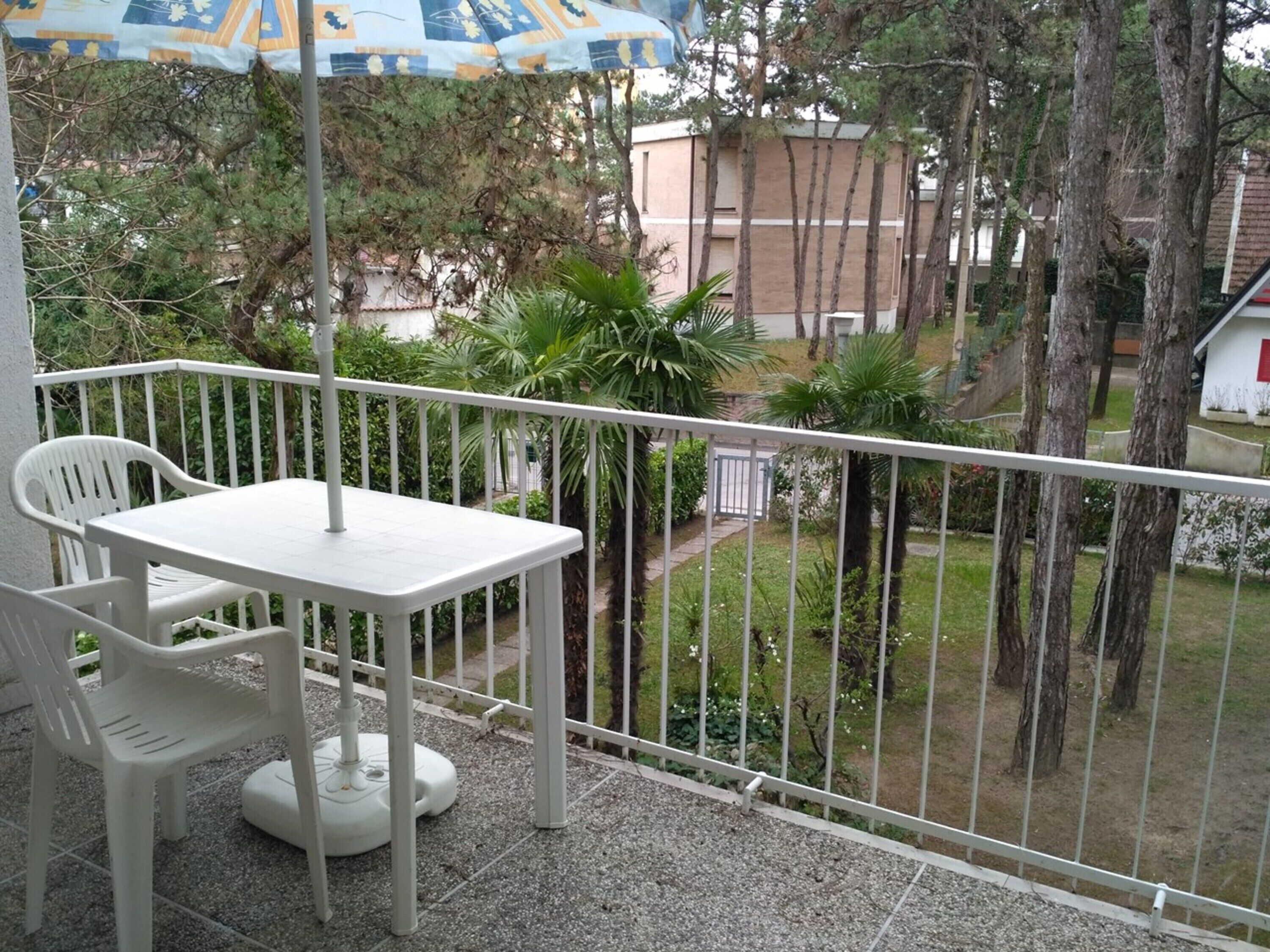 A balcony with a white table and chairs, surrounded by a white railing.