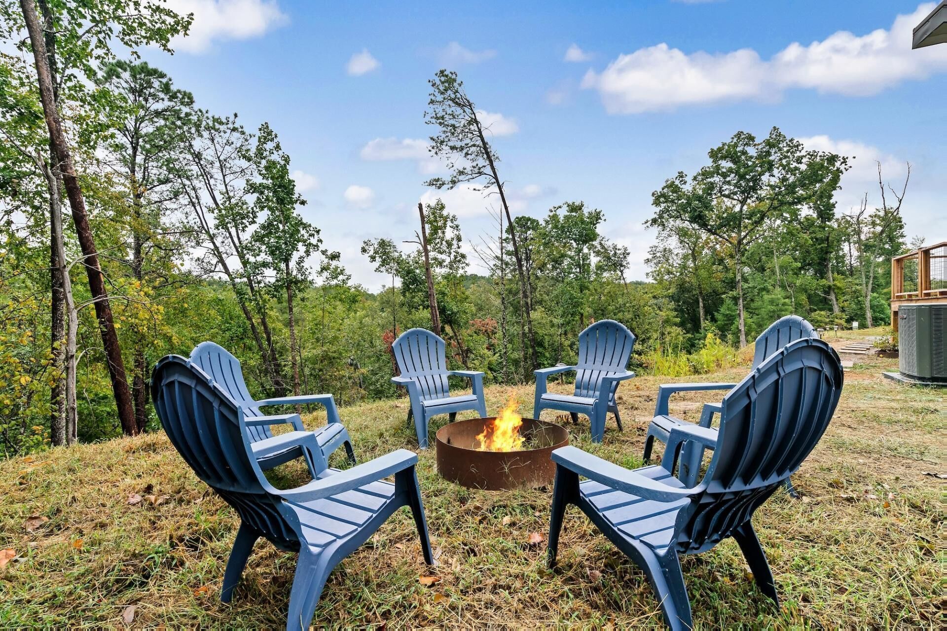 Un foyer extérieur entouré de quatre chaises Adirondack disposées autour.