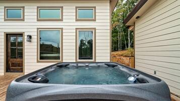 Una casa moderna con un jacuzzi en el patio trasero.