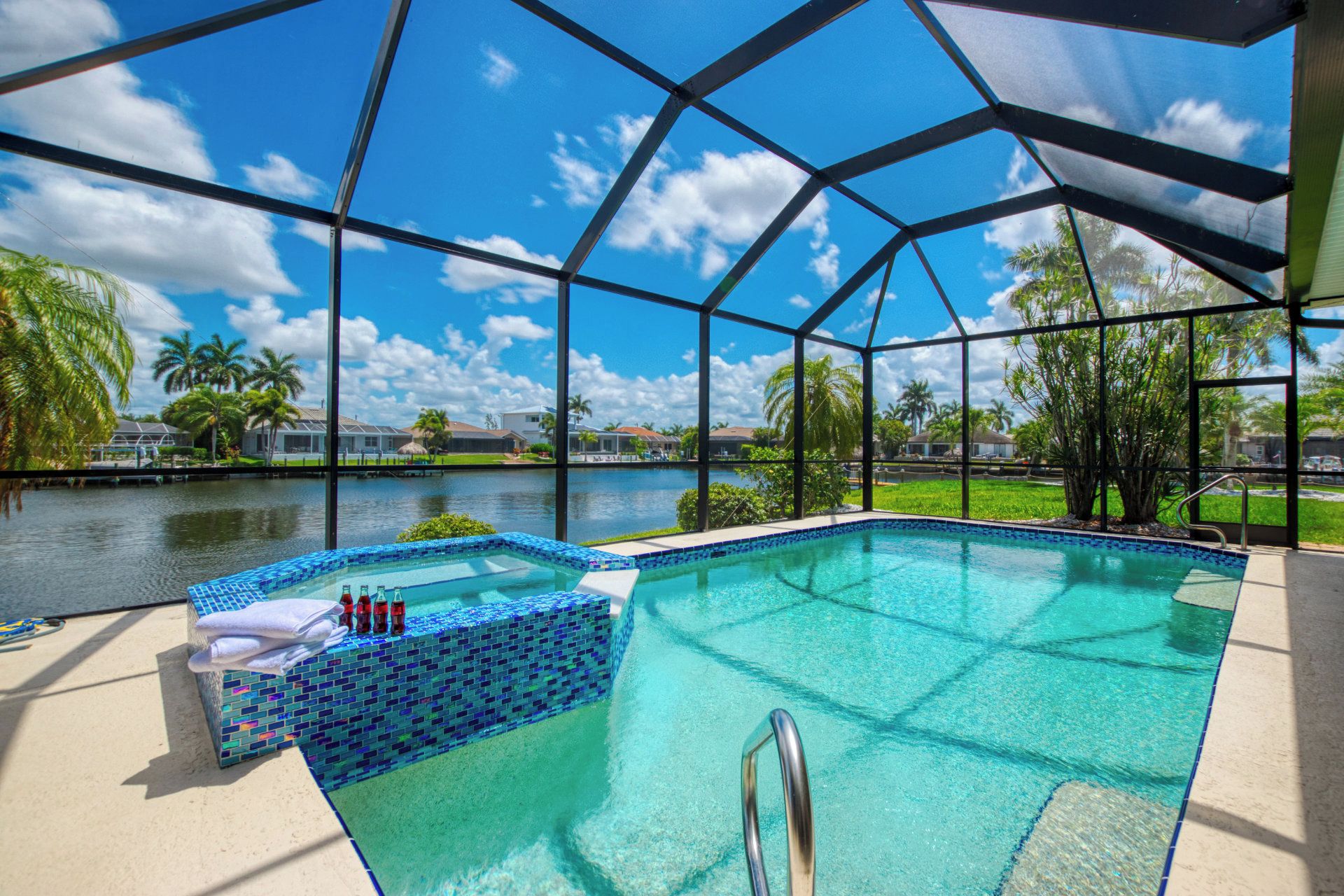 Una piscina cristalina con borde de azulejos, una silla de piscina y una botella de agua.