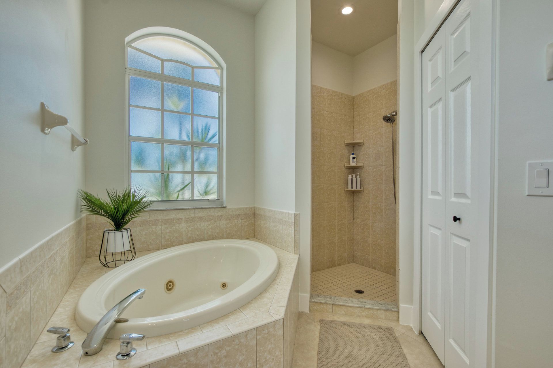 A bathroom with a bathtub, a shower, a window, and a door.