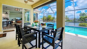 Un espace repas comprenant une table, des chaises et donnant sur une piscine.