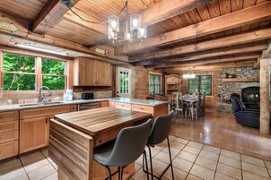 Interior de una cabaña de madera con cocina, comedor y chimenea de piedra.