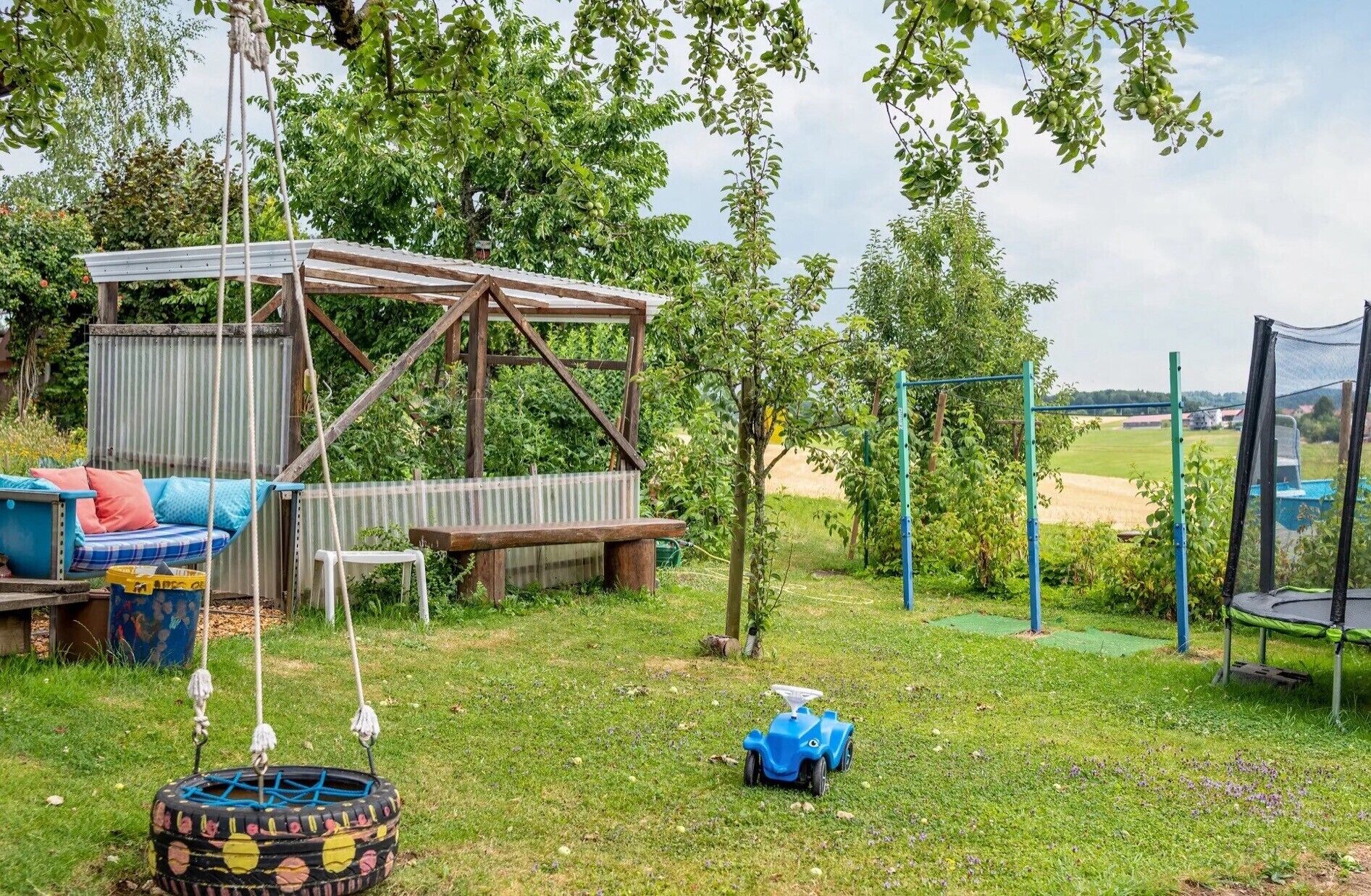 Un ambiente esterno rustico con una casetta di legno, un'altalena e un trampolino.