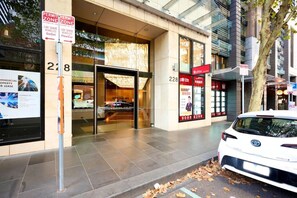 Ein Gewerbegebäude mit Glasfassade, Nummer 228, und ein weißes Auto vor der Tür.