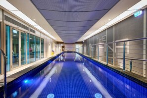 Ein Innenpool mit Glaswänden, gefliestem Boden und einer Decke mit Rastern.
