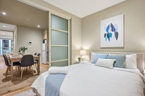 Ein Hotelzimmer mit einem Bett, einem Schreibtisch mit Stühlen, einem Essbereich und einer Küche.