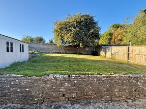 A brick wall, a grassy yard, and a tree. - Swanage Prospect | Dog friendly, Garden, Parking & 10 minute walk to beach (Swanage)