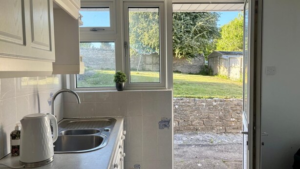 Cozinha com pia, chaleira e janela com vista para um jardim.