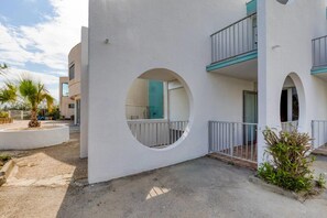 Un edificio moderno con finestre circolari, balconi e un cortile lastricato.
