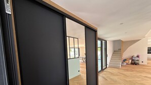 Een modern interieur met een schuifdeur, houten vloeren en een trap naar een hoger gelegen verdieping.