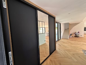 A modern interior with a sliding door, wooden flooring, and a staircase leading to an upper level. - Villa Zoliette (Batz-sur-Mer)
