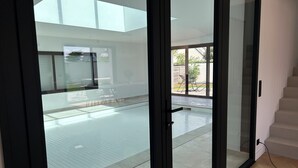 Een modern interieur met een glazen deur die leidt naar een buitenruimte met een zwembad en tuinmeubilair.