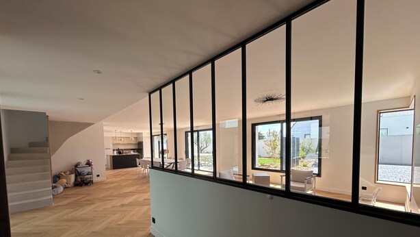 Een modern interieur met een trap, een eethoek met witte stoelen en een keuken met houten keukenkastjes.