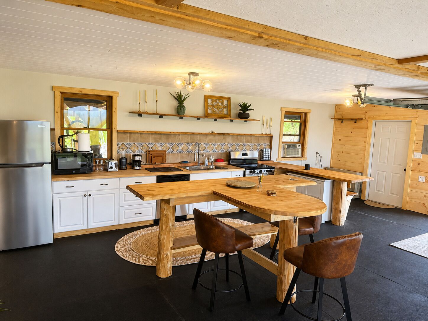 A modern kitchen with wooden countertops, a stainless steel refrigerator, and a central island with stools.