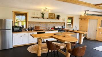 A modern kitchen with wooden countertops, a stainless steel refrigerator, and a central island with stools.