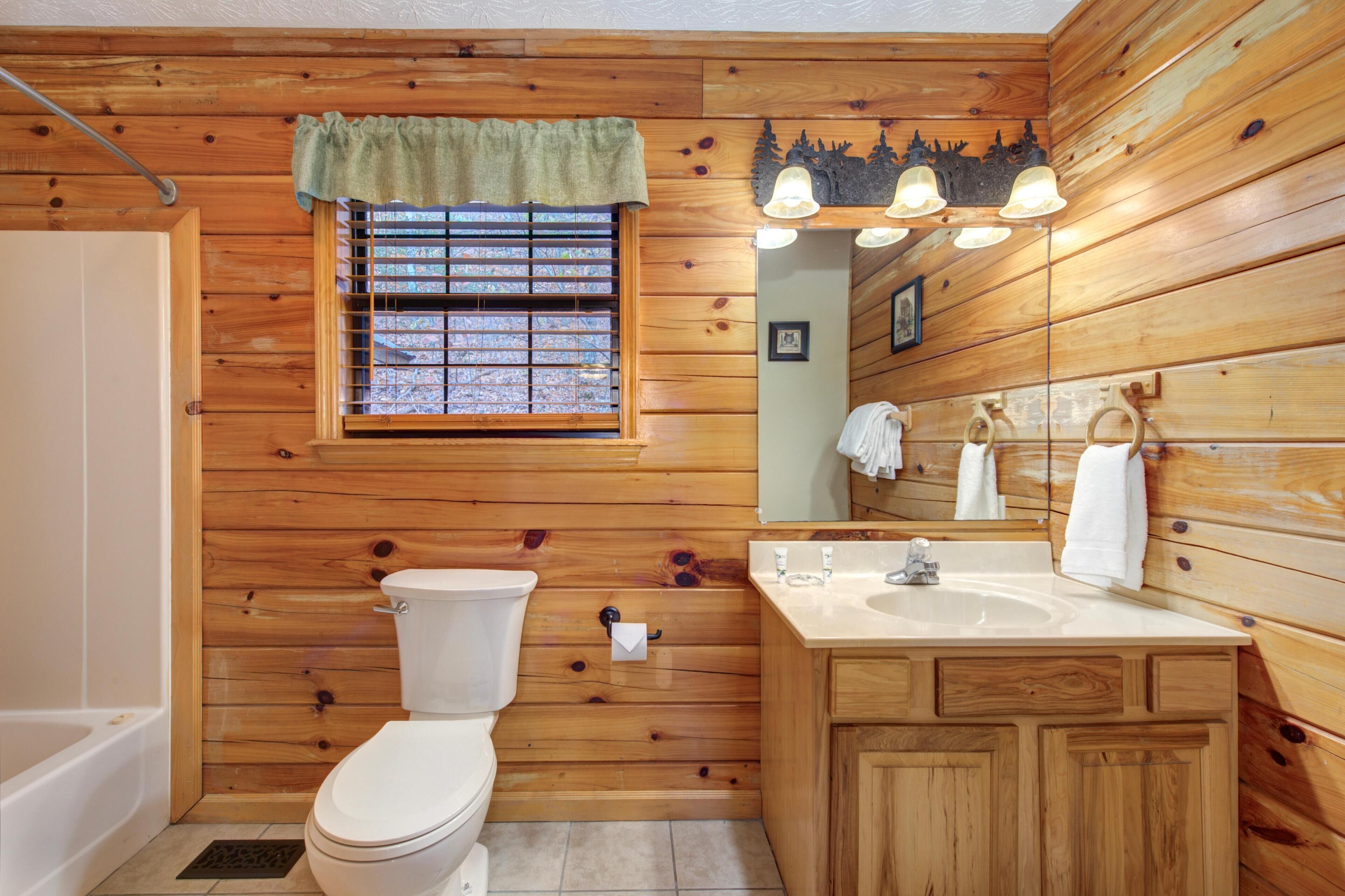 Un baño con paneles de madera, un inodoro, un lavabo y una ventana.