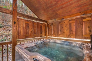Ein hölzernes Whirlpool mit einer Holzterrasse und Geländern, umgeben von Bäumen.