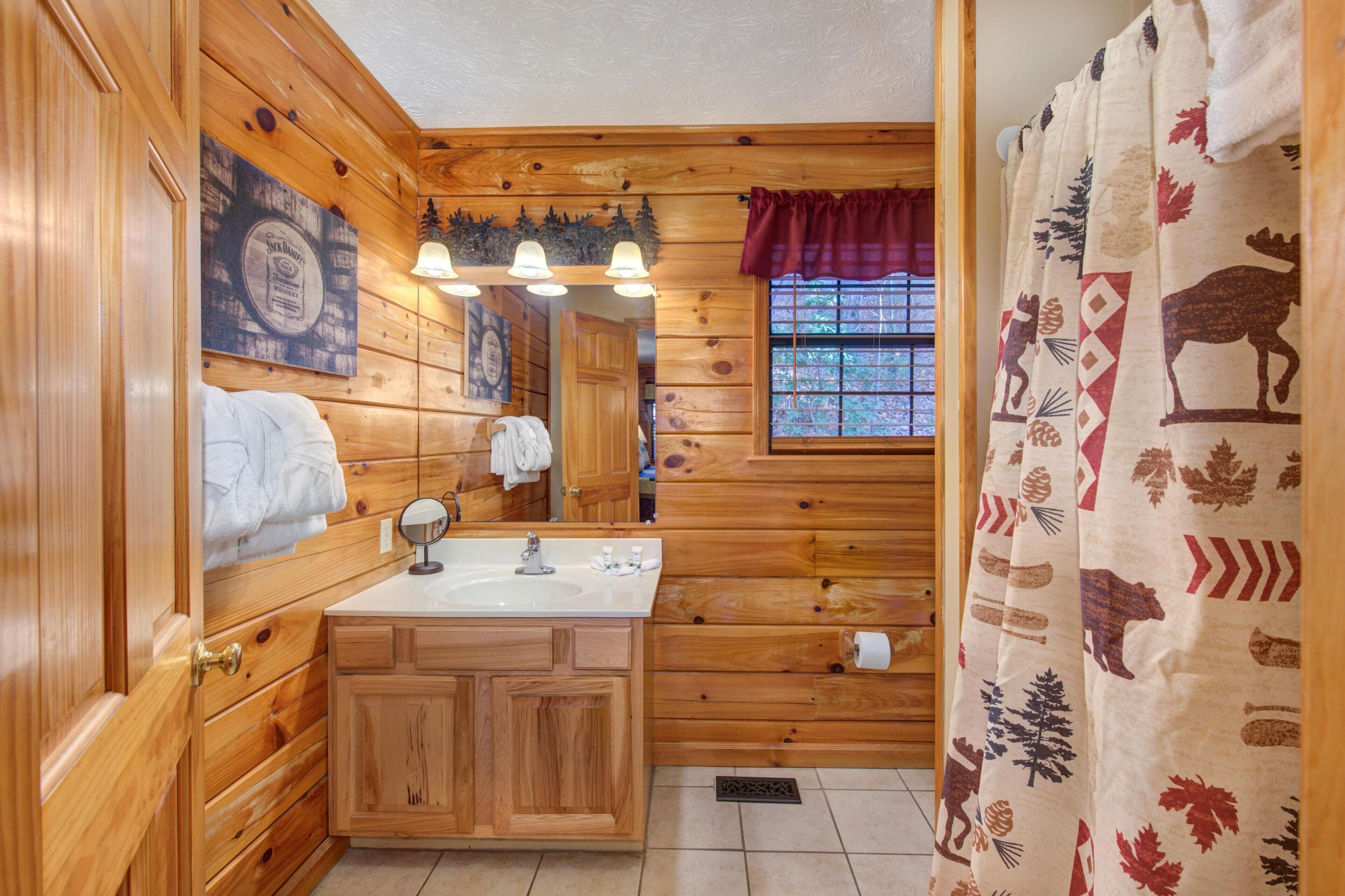 Une salle de bain rustique, aménagée dans une cabane en bois, avec un lavabo, un miroir et un porte-serviettes.