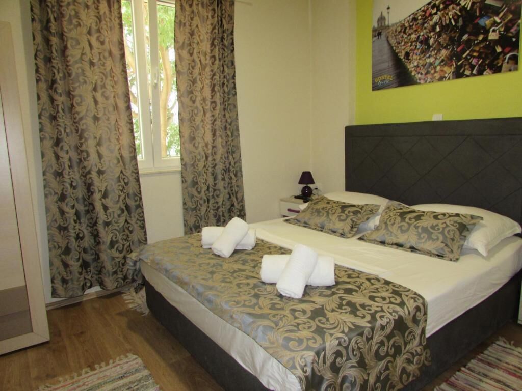 A hotel room with a bed, curtains, a nightstand, and a wall with a lock collection.