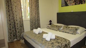 A hotel room with a bed, curtains, a nightstand, and a wall with a lock collection.