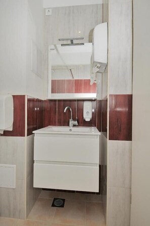 A bathroom with a white sink, a mirror, and a towel rack.