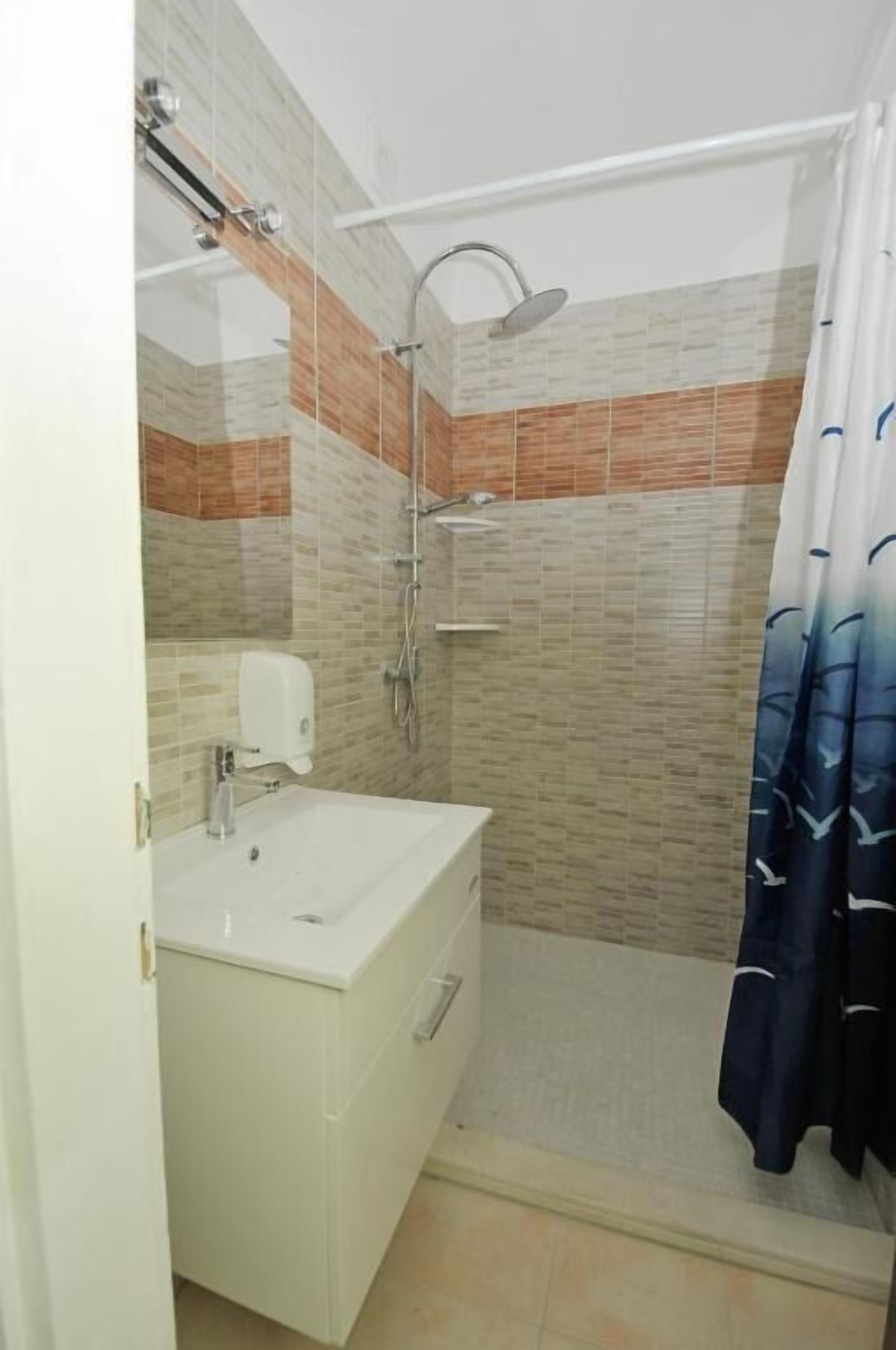 Ein Badezimmer mit Dusche, Waschbecken und Spiegel.