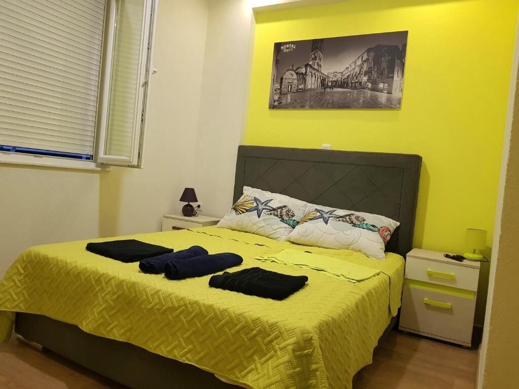 Una habitación de hotel con cama, mesita de noche, lámpara y un cuadro colgado en la pared.
