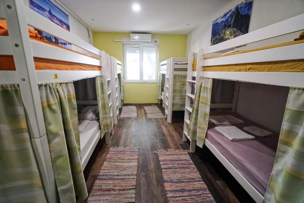 A dormitory room with bunk beds, a window, and a door.