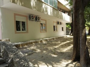 A building with multiple windows, air conditioning units, and a stone wall.