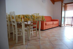 Ein Essbereich mit Tisch, Stühlen, einer Couch und einem Balkon.