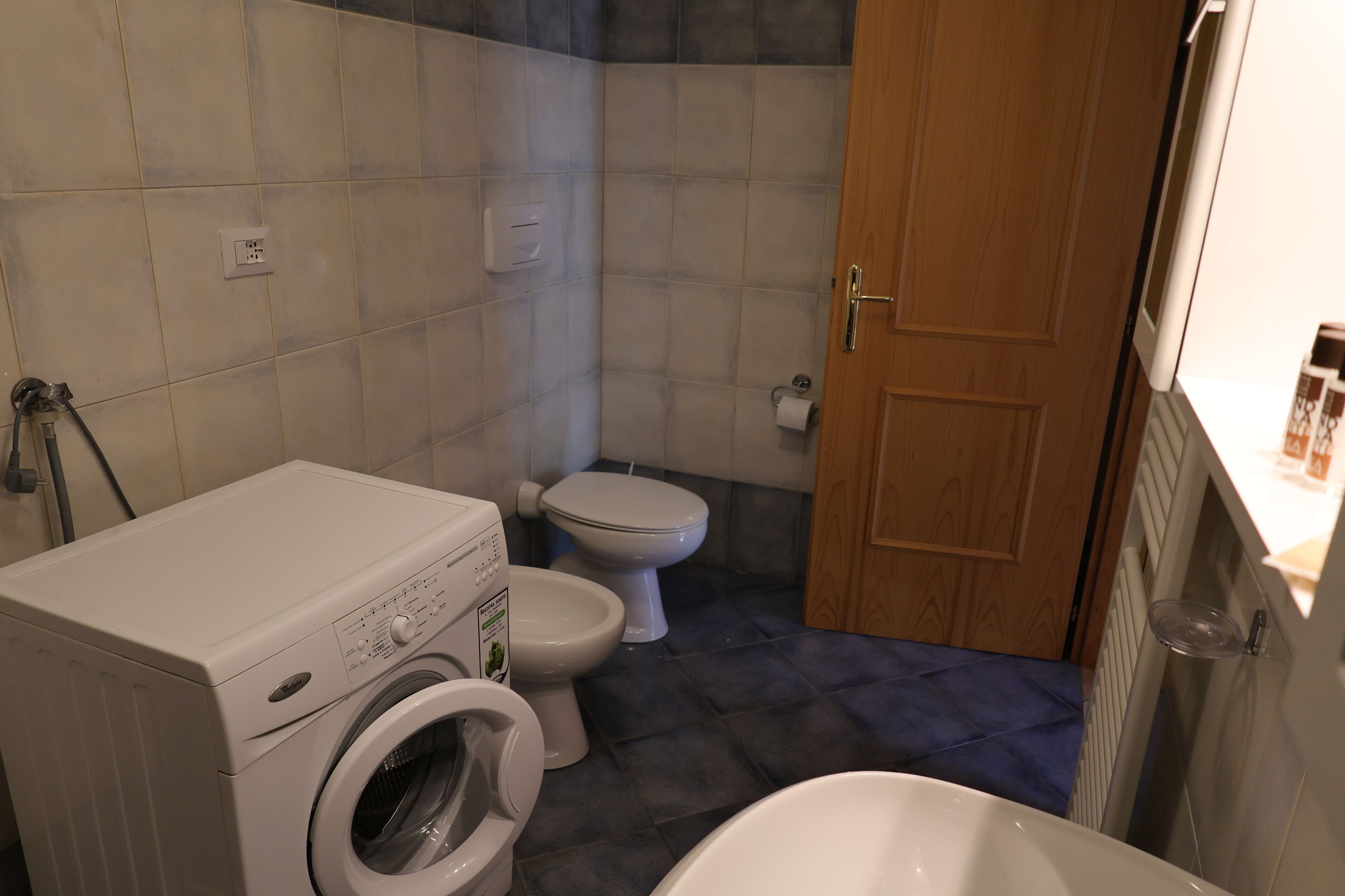 A compact bathroom with a washing machine, toilet, and bathtub.