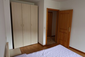 Ein Schlafzimmer mit Bett, Kleiderschrank und einer Tür zu einem anderen Raum.
