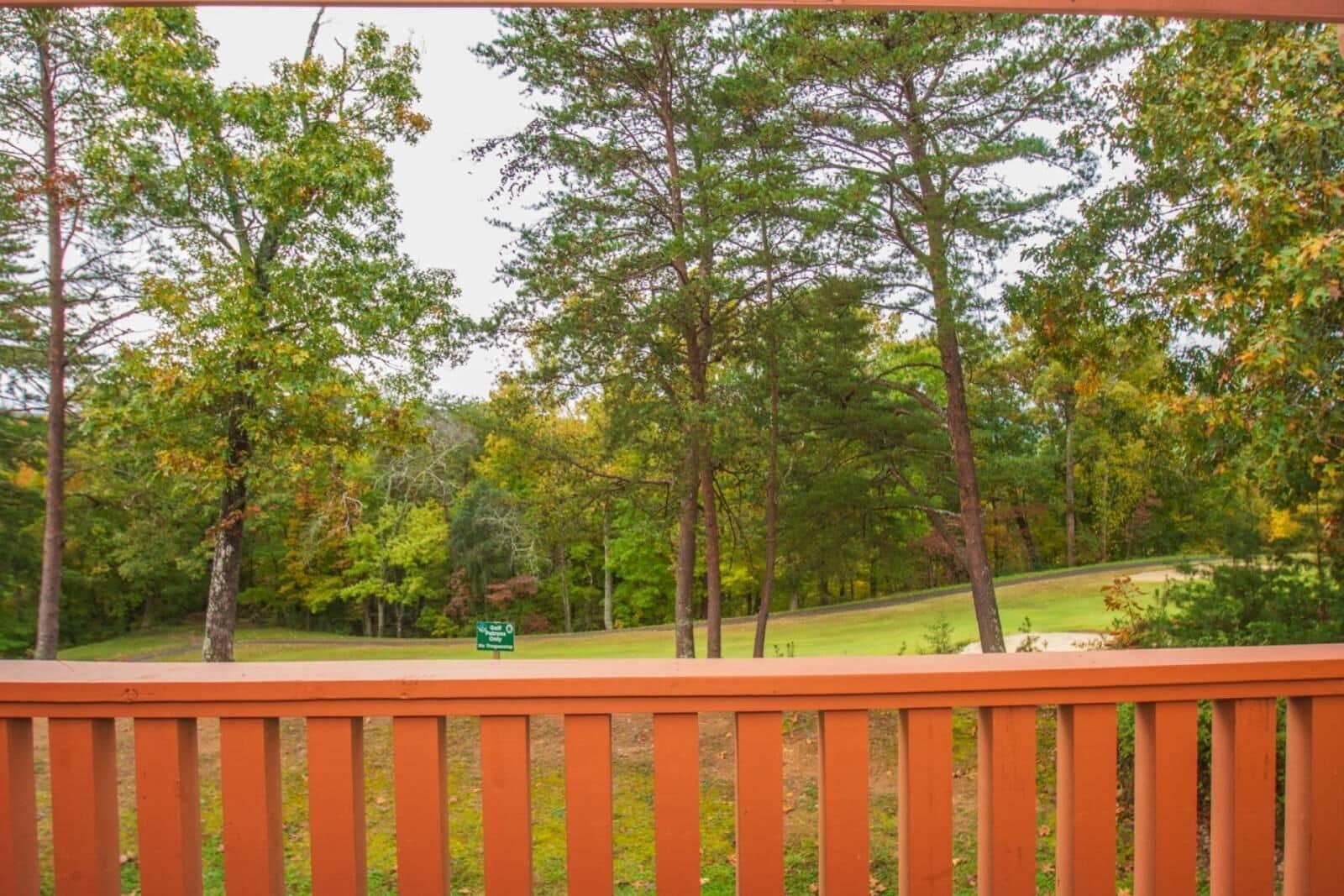 Una terraza de madera con vistas a zona boscosa y un letrero verde.