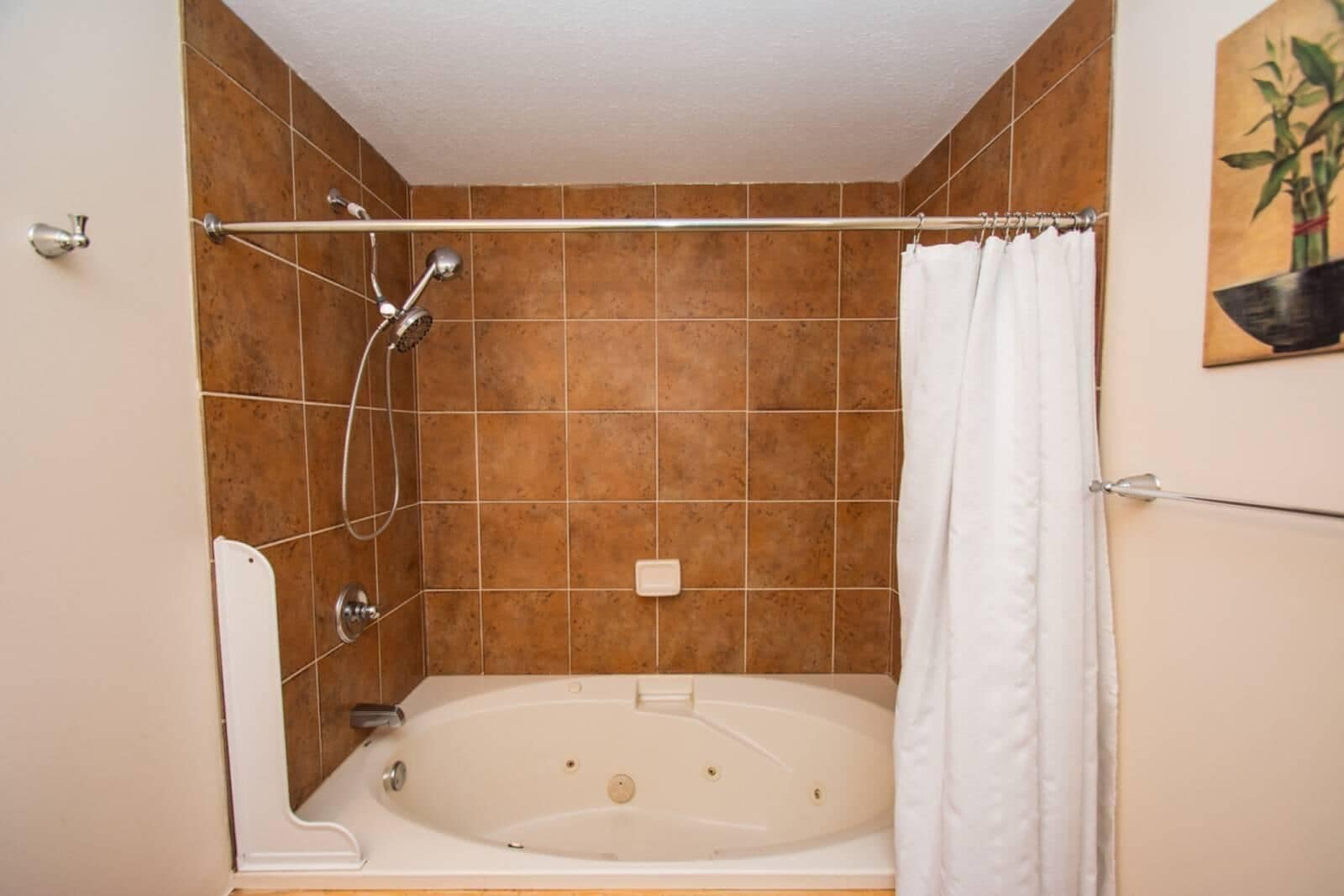 A bathroom with a bathtub, shower, and a white curtain.