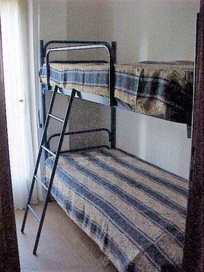 Een stapelbed met een ladder, een gestreept matras en een effen muur.