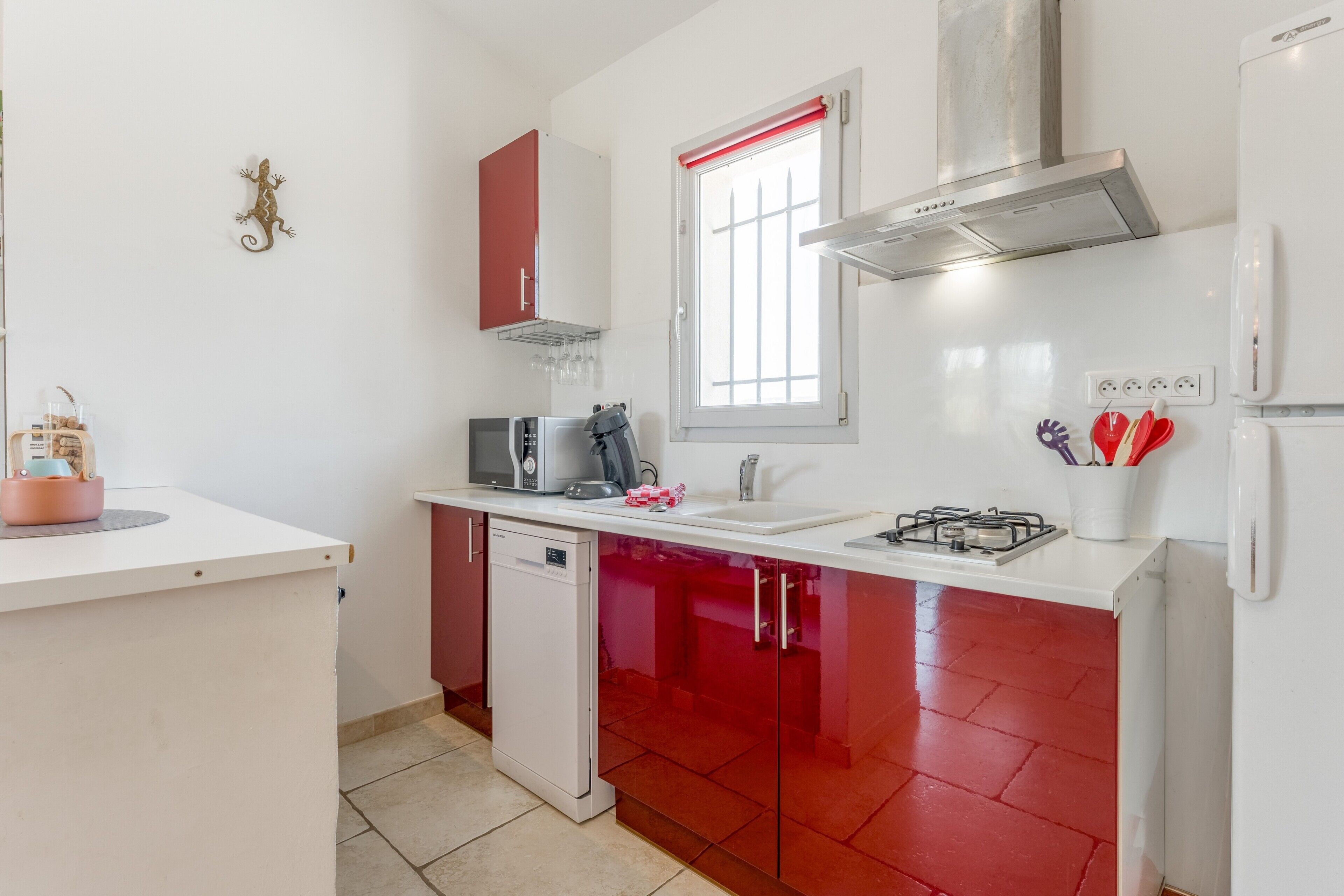Una cocina equipada con lavavajillas, microondas, estufa y armarios rojos.