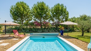 Ein rechteckiger Pool mit glasklarer, blauer Wasserfläche, umgeben von einem mit Kies befestigten Deck.