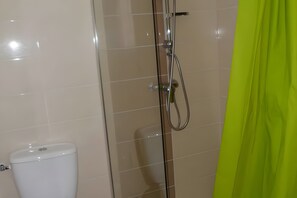 A bathroom with a glass shower enclosure, a toilet, and a green shower curtain.